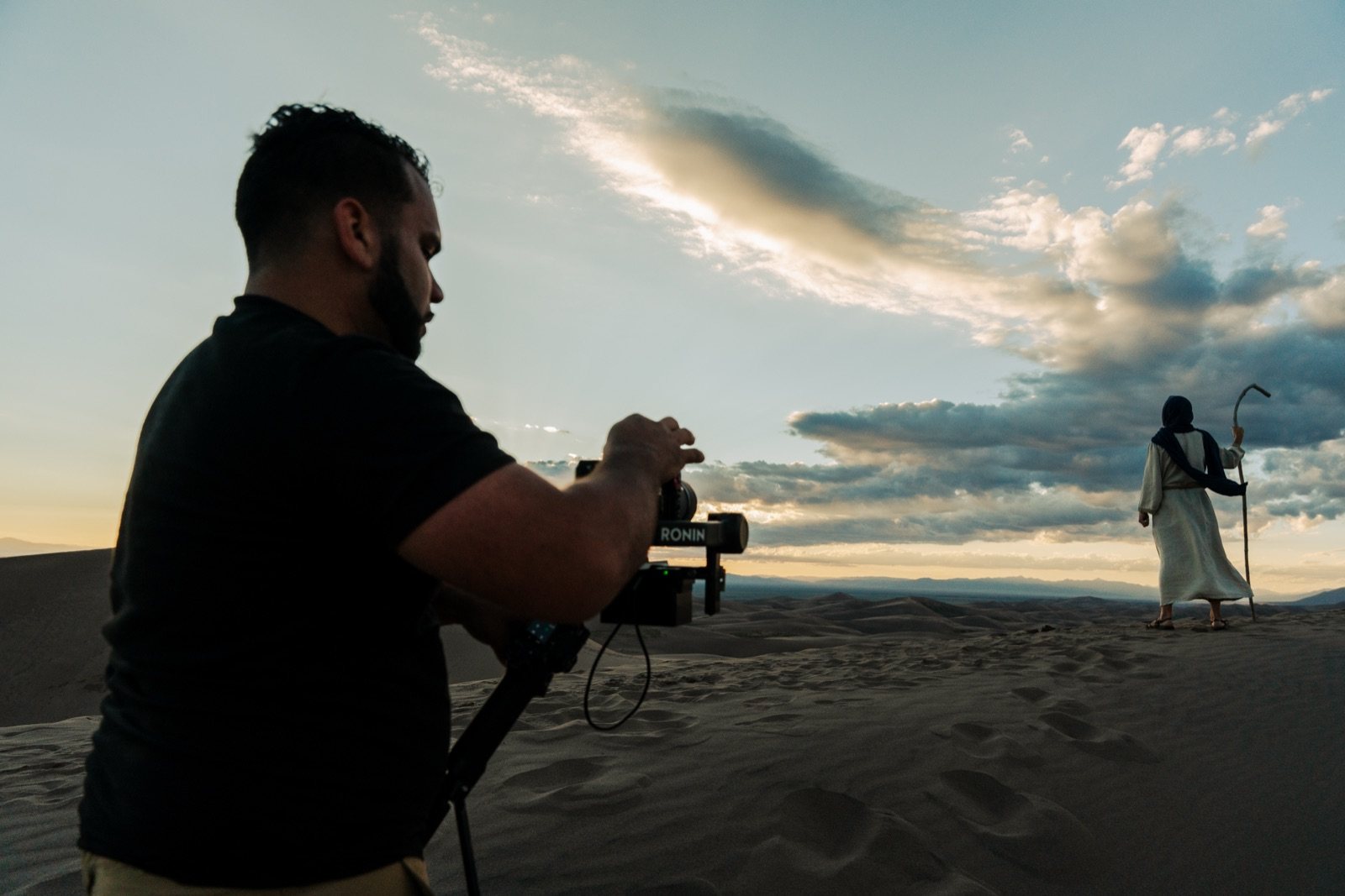 Shadai Perez filming an actor on a sand dune at sunset